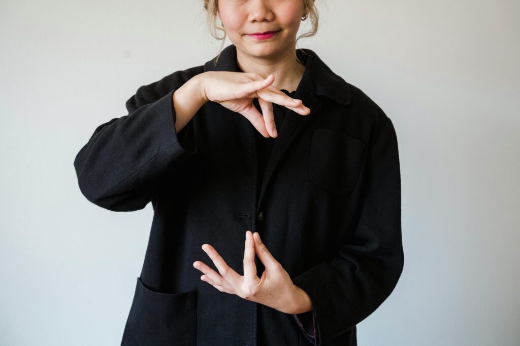 A woman in a studio using sign language against a white background.